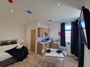 a bedroom with a bed and a table and a kitchen at Flat 2, Modern Studio apartment, Tynte Hotel, Mountain Ash in Quakers Yard