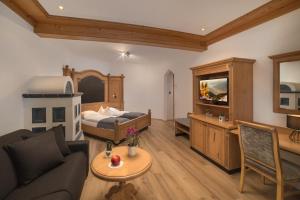 Sala de estar con sofá, cama y mesa en Schönblick - Sport & Active Hotel en Brunico