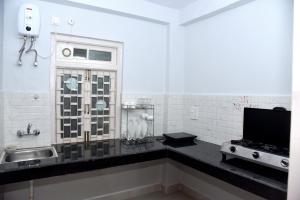 a bathroom with a sink and a television on a counter at Samriti Apartments in Shimla