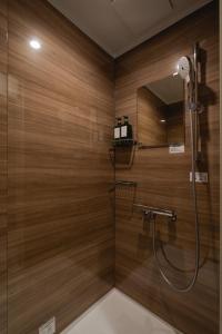 ein Badezimmer mit Holzwänden und einer Dusche mit Spiegel in der Unterkunft 宿坊-地蔵院 in Kurayoshi