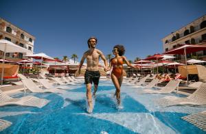un hombre y una mujer entrando en una piscina en Hard Rock Hotel Marbella - Puerto Banús Adults Recommended, en Marbella