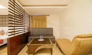 uma sala de estar com um sofá, uma mesa e uma cadeira em FabHotel Oakwey Inn Indiranagar em Bangalore