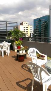 un balcón con sillas blancas, mesas y edificios en Taipei Discover Hostel en Taipéi
