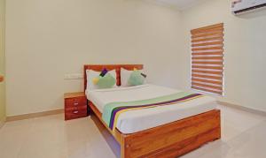 a bedroom with a bed with a wooden headboard and a window at Treebo Trend Sreepathi Nirmalyam 1 Km From Guruvayoor Railway Station in Guruvāyūr
