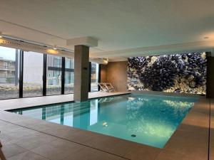 een zwembad in een gebouw met een aquarium bij The Sailor, full sea view, use of hotel swimming pool and sauna in Cadzand