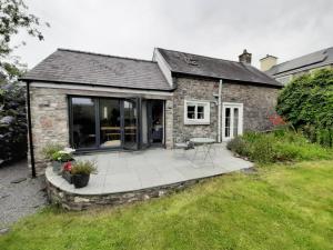 uma casa de pedra com um pátio no quintal em Pass the Keys Character country cottage with scenic castle views em Llandeilo