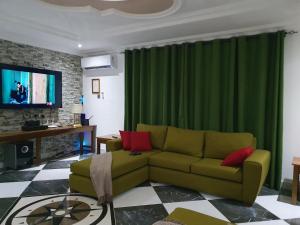 a living room with a couch and a green curtain at Villa Nelomoor in Kwabenya