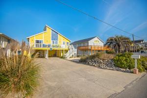 a yellow house with a porch and a driveway at Living the Dream in Surf City