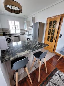 a kitchen with a granite counter top and two chairs at Casa Cantábrico in Castro-Urdiales