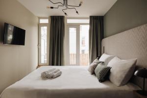 a bedroom with a large white bed with a window at Adam Suites Hotel in Amsterdam