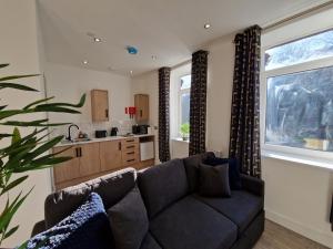 a living room with a couch and a kitchen at Flat 3. Modern one bed apartment, Tynte Hotel, Mountain Ash in Quakers Yard