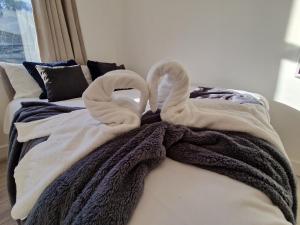 two towel swans sitting on top of a bed at Flat 3. Modern one bed apartment, Tynte Hotel, Mountain Ash in Quakers Yard
