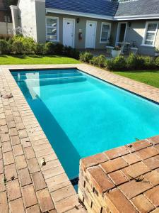a swimming pool with blue water in front of a house at Eagle Cove in Honeydew