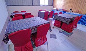 a room with two tables and chairs and red chairs at Treebo Trend Sreepathi Nirmalyam 1 Km From Guruvayoor Railway Station in Guruvāyūr