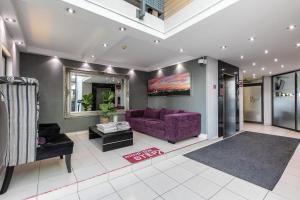 a living room with a purple couch and a mirror at RAD STAYS - 60 Westpoint 89 Grayston Dr Morningside in Johannesburg