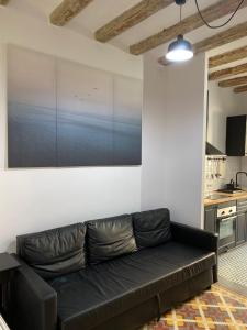 a black couch in a living room with a painting on the wall at Spacious Modern Apartment in the Vibrant El Raval in Barcelona