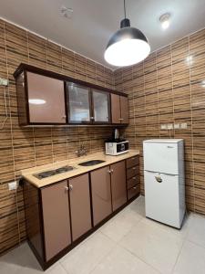 a kitchen with a white refrigerator and wooden walls at أجنحة ورد للشقق المخدومة in Khamis Mushayt