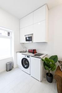 a white kitchen with a washing machine and a washer at Loft situado cerca del Santiago Bernabéu in Madrid