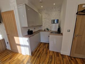 a kitchen with white cabinets and a wooden floor at Flat 5. Modern studio apartment, Tynte Hotel, Mountain Ash in Quakers Yard