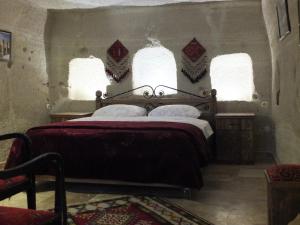 a bedroom with a large bed with two windows at Anatolia cave hotel Pension in Göreme