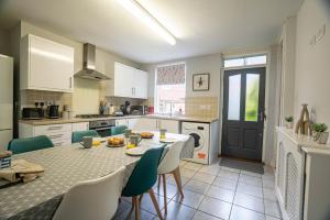 a kitchen with a table and chairs and a kitchen with white cabinets at The Becket - Three Bedroom City Centre House with Parking in Canterbury