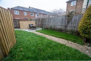a backyard with a fence and a table and chairs at The Becket - Three Bedroom City Centre House with Parking in Canterbury