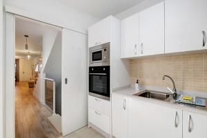 uma cozinha com armários brancos e um lavatório em Casa Reguemar em Arrecife