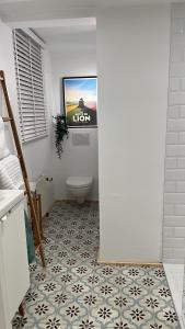 a bathroom with a toilet and a tv on the wall at Le Cottage in Lasne