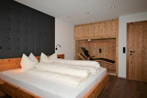 - une chambre avec un grand lit et des draps blancs dans l'établissement Zirbentraum, à Biberwier