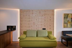 - un canapé vert dans une pièce dotée d'un mur en briques dans l'établissement Zirbentraum, à Biberwier