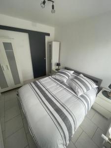 1 dormitorio con 1 cama blanca grande con almohadas a rayas en Les Jonchères, en Luxeuil-les-Bains