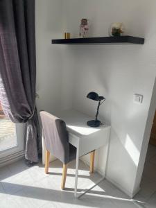 einen Schreibtisch mit einer Lampe und einem Stuhl neben einem Fenster in der Unterkunft Les Jonchères in Luxeuil-les-Bains