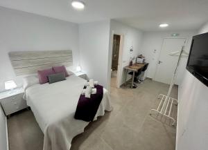 1 dormitorio con 1 cama blanca grande con almohadas moradas en Apartamentos Los Cabezuelos, Dream Views, en Arcos de la Frontera