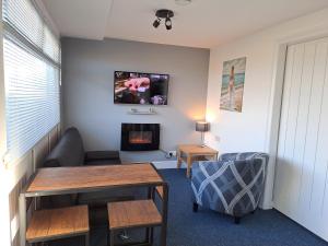 a living room with a table and a fireplace at Sandhaven Beach Chalets in South Shields