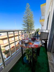 a table and chairs on a balcony with a tree at Cantinho dos avós in Fuzeta