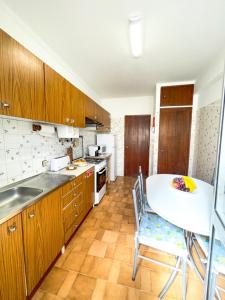 a kitchen with a white table and chairs in it at Cantinho dos avós in Fuzeta