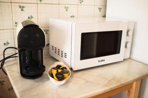 a microwave sitting on top of a counter next to a bowl at Cantinho dos avós in Fuzeta