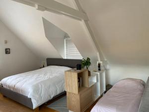 sypialnia na poddaszu z łóżkiem i oknem w obiekcie Le Cottage w mieście Lasne