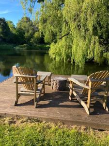 Cwmbach Lodge luxury B&B في Glasbury: كرسيين خشبيين جالسين على رصيف بجانب البحيرة