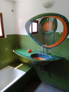 Baño de azulejos verdes con lavabo y espejo en casita moderna frente al bosque en Mar del Plata
