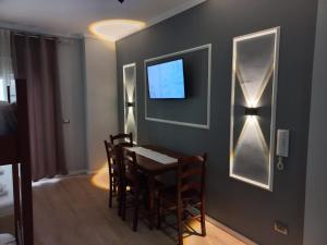 a dining room with a table and a tv on a wall at Lungomare Apartament Sea View in Vlorë
