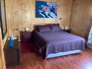 1 dormitorio con 1 cama y una pintura en la pared en El Viloche - Casa de campo con tinaja, en Puerto Montt