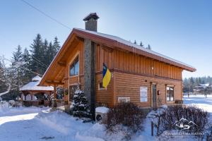 a log cabin in the snow with a flag on it at Girska Hatyna Vorohta in Vorokhta