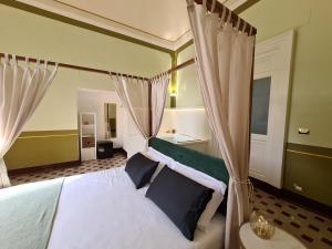 a bedroom with a bed with white sheets and black pillows at Toscano Palace Luxury Rooms Catania in Catania