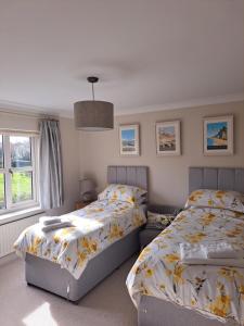a bedroom with two beds and a window at Bramble Lodge in Blakeney