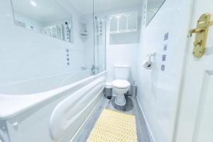 a white bathroom with a toilet and a yellow rug at Modern 4-Level Townhouse for 8 Free Parking Bournemouth in Bournemouth