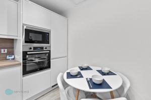a white kitchen with a white table and chairs at 3 Bed- The Barracks in Plymouth
