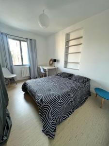 een slaapkamer met een bed met een zwart-witte deken bij La Petite Échappée - Proche mer in La Genilliere
