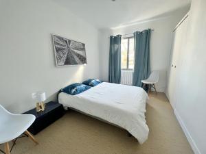 a bedroom with a bed with blue pillows and a window at La Petite Échappée - Proche mer in La Genilliere