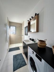 een badkamer met een wasmachine en een wastafel bij La Petite Échappée - Proche mer in La Genilliere